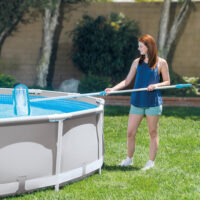 Donna pulisce piscina fuori terra con retino