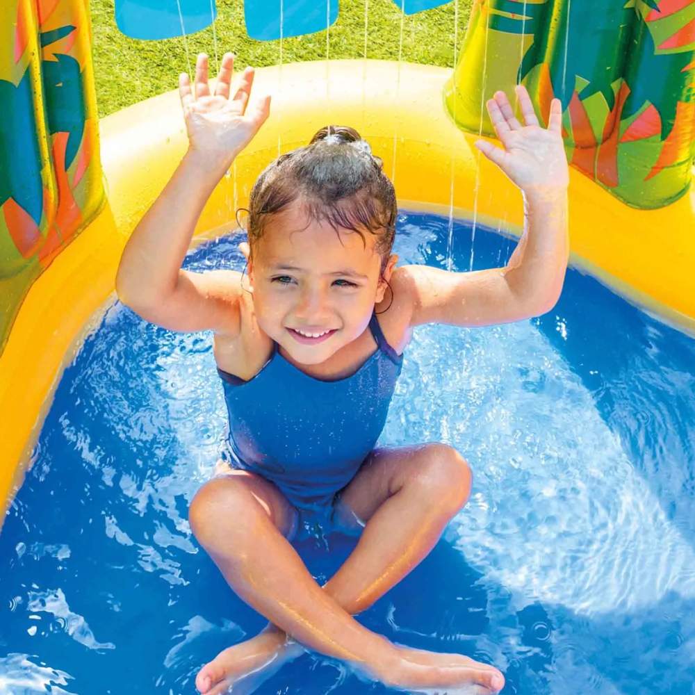 Bambina sorridente in piscina gonfiabile con spruzzi