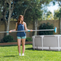 Donna pulisce piscina fuori terra in giardino