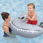 Bambino gioca in piscina con gonfiabile squalo
