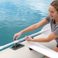 Donna fissa un remo a un gommone sull'acqua