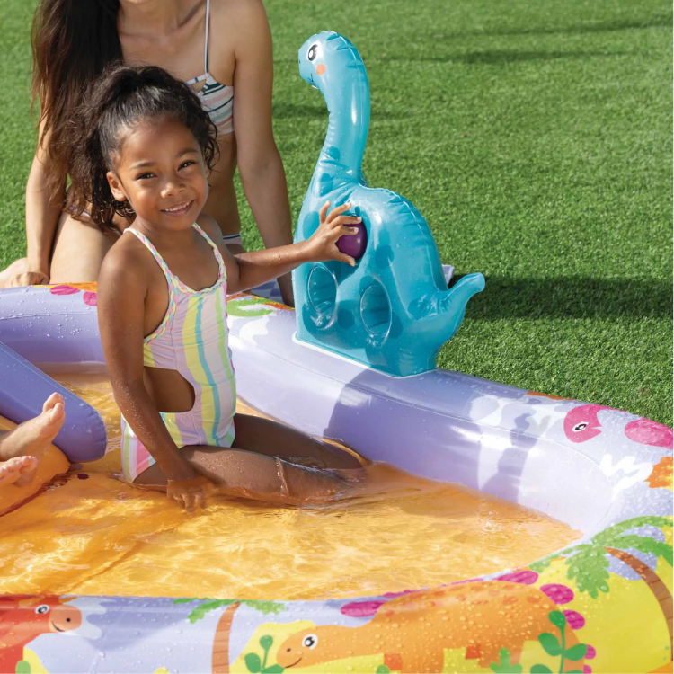 Bambina sorride in piscina gonfiabile con dinosauro azzurro