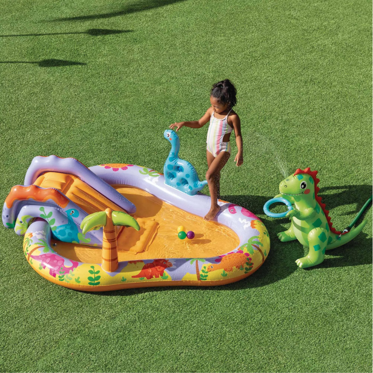 Bambina gioca in piscina gonfiabile con dinosauri